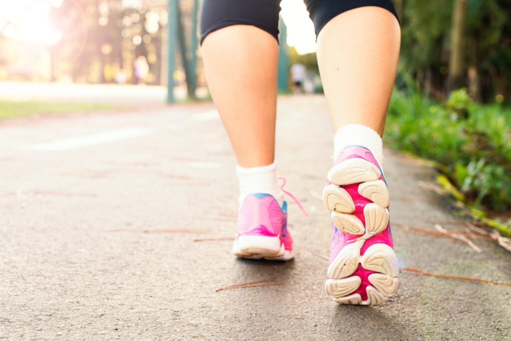 zdjęcie nóg kobiety idącej w różowych sportowych butach